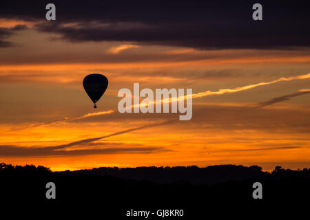 Bristol, Royaume-Uni. 13e Août 2016. L'ascension de la Bristol Balloon Fiesta Festival arrive enfin en cours après des retards en raison des vents violents depuis le jeudi. Un magnifique coucher de soleil a agi comme une toile de fond à plusieurs ballons qui a pris au ciel après les organisateurs du festival ont donné le feu vert pour décoller. Les ballons dérivaient sur la ville de Bristol vers les hameaux de Bitton et Keynsham avant de toucher par champs aléatoires et de parc de nombreux kilomètres de l'Ashton Court site du festival. Credit : Wayne Farrell/Alamy Live News Banque D'Images