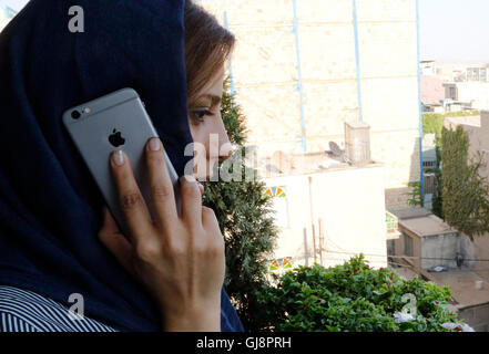 Téhéran, Iran. 13e Août 2016. Une jeune femme à l'aide d'un iPhone à Téhéran, Iran, 13 août 2016. Les iPhones sont très populaires en Iran, mais disponible uniquement en raison de l'illégalement les sanctions américaines. Le gouvernement iranien prévoit de fermer le marché illégal et l'importation de la cuisine via des entreprises sélectionnées. Néanmoins, US-marchandises américaines ne sont toujours pas autorisés à être importés en Iran en raison des sanctions. PHOTO : FARSHID M. BINA/dpa/Alamy Live News Banque D'Images