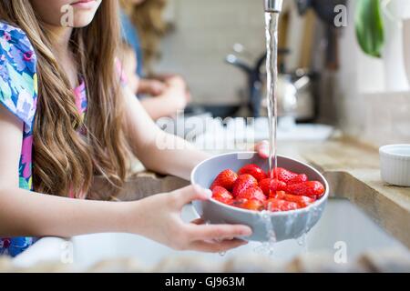 Parution de la propriété. Parution du modèle. Girl washing fraises fraîches dans l'évier. Banque D'Images