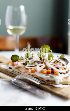 Un pain plat ou salade de fromage de chèvre et pizzetta avec radis, l'oignon rouge, squash et feuilles de bébé Banque D'Images