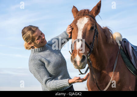 Jeune femme prendre soin de son cheval Banque D'Images