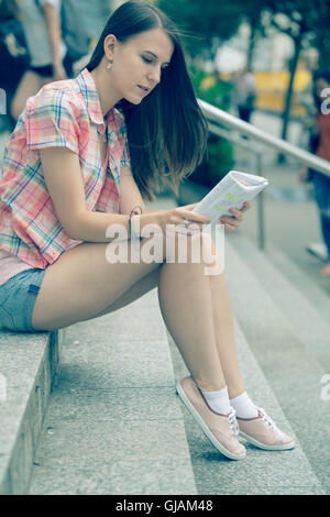 L'élève lit fille assise sur l'escalier notes. Photo couleur Banque D'Images