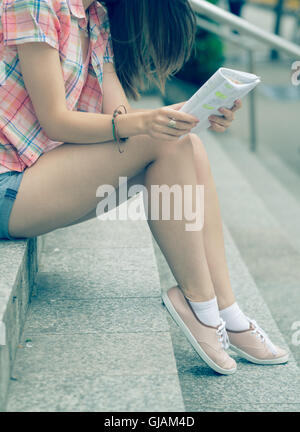 L'élève lit fille assise sur l'escalier notes. Photo couleur Banque D'Images