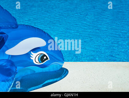 Vacances d'été de couleurs vives contexte montrant un dauphin gonflable sur le côté de la piscine sur une chaude journée ensoleillée, Banque D'Images