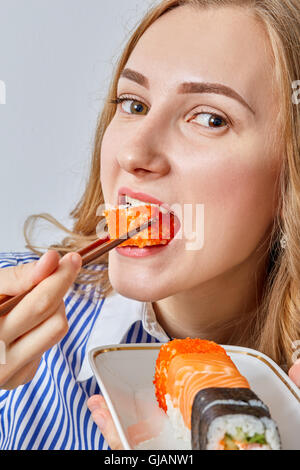 Fun young girl eating sushi sur fond blanc Banque D'Images