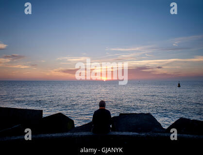 L'homme est de regarder le coucher du soleil sur le quai, Scheveningen, à La Haye, Pays-Bas Banque D'Images