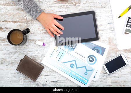 La main d'une femme à une table useing une tablette. Banque D'Images