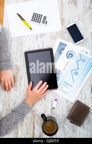La main d'une femme à une table useing une tablette. Banque D'Images