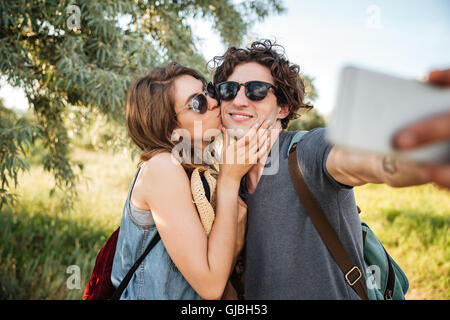 Young smiling couple heureux avec sacs à dos randonnée dans la forêt et faire selfies Banque D'Images