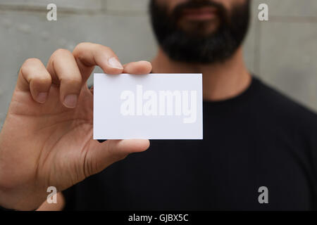 Homme barbu portant des Casual Black Tshirt montrant Case White Carte.Fond flou prêt Corporate Information privée.Maquette horizontale. Banque D'Images