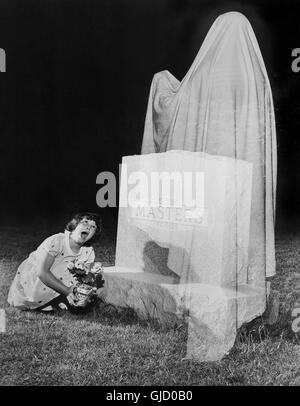 Une fille de placer des fleurs sur une tombe du cimetière est surpris par un fantôme dans cette photographie de nuit 1960 créé en faisant une double exposition sur le même film. Le photographe figuré un paramètre d'exposition au flash à la jeune fille et pierre tombale, et réglez l'objectif de l'ouverture (f/stop) à la moitié de cette exposition. Tandis que la jeune fille a tenu, encore une personne dans une feuille blanche posée en face de la pierre tombale et une 2e exposition flash ont été faites à la même f/stop. Ces deux demi-prévu après une exposition correcte. Ce qui a été enregistré au cours de la 1ère exposition devint visible derrière la feuille pour créer l'effet fantôme. Banque D'Images