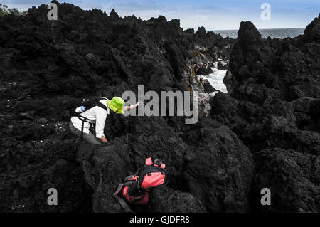 Une femme monte sur les roches volcaniques près d'un bassin de marée, Big Island, Hawaii Banque D'Images