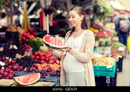 Pregnant woman holding watermelon at street market Banque D'Images