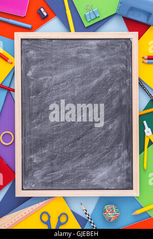 Retour à l'école contexte avec blank chalkboard. Variété de fournitures scolaires avec tableau noir en blanc. Mise à plat. Copy space Banque D'Images