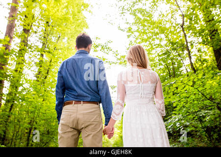 Beau couple de mariés à l'extérieur en vert forêt. Vue arrière. Banque D'Images