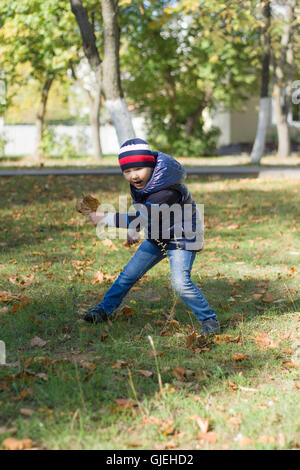 Le petit garçon marche sur la ville d'automne avec des feuilles jaunes Banque D'Images