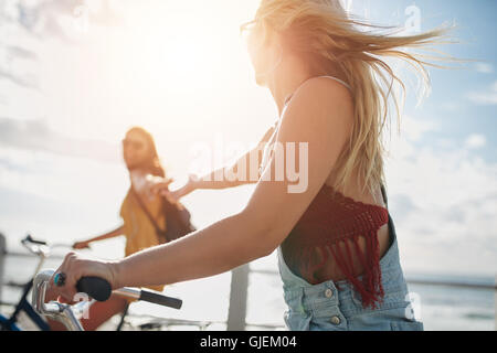 Deux jeunes femmes friends riding leur vélo sur la promenade du bord de mer. Cycliste féminine appréciant en vtt sur une journée d'été. Banque D'Images