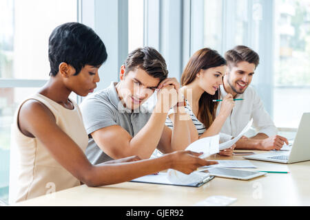 Groupe de jeunes gens d'affaires concentré assis et travailler sur des documents dans Office Banque D'Images