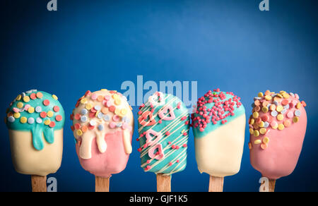 Cake pops dans la crème glacée forme sur fond bleu Banque D'Images