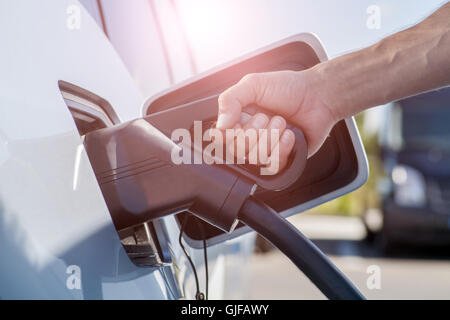 Image couleur de la main d'un homme prêt à charger une voiture électrique. Banque D'Images