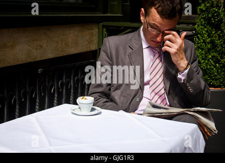 Un homme lit le journal avec un café à Bruxelles, Belgique Banque D'Images