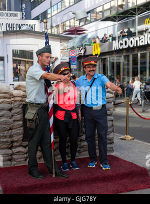 Tourist posant pour une photographie à Checkpoint Charlie, Mitte, Berlin, Allemagne. Banque D'Images