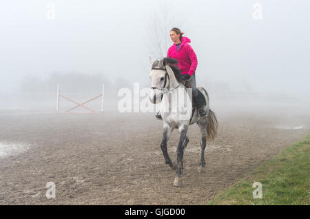 Jeune femme équitation dans le brouillard Banque D'Images