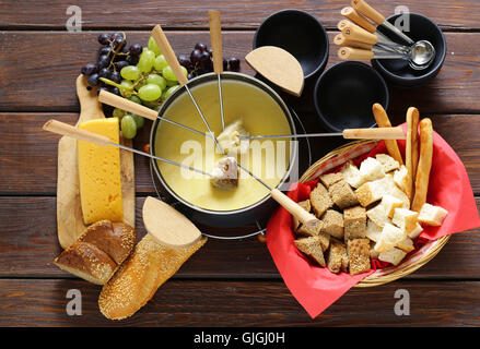 Set d'ustensiles traditionnels pour la fondue, avec du pain, du fromage et du raisin Banque D'Images