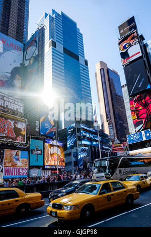 New York jaune des taxis passent par Times Square que la lumière du soleil se reflète sur des immeubles de grande hauteur Banque D'Images