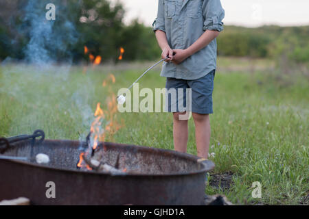 Boy toasting un marshmallow sur un feu de camp Banque D'Images