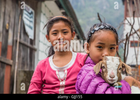 Le Népal, les filles avec chèvre dans village de montagne. Banque D'Images