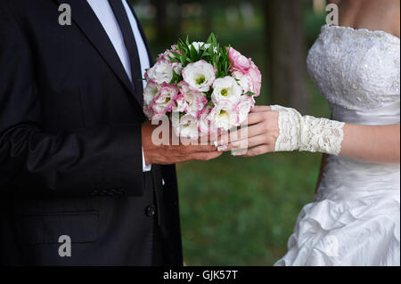 Le marié embrasse mariée, et elle détient un bouquet dans ses mains Banque D'Images