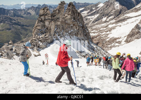 Les personnes équipées avec des casques de la descente d'une route dans la neige un jour d'été au glacier de Hintertux, Zillertal, Autriche Banque D'Images