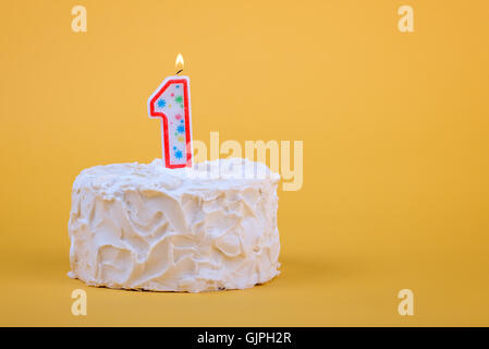 Gâteau blanc gelé avec 1 bougie allumée sur le dessus. Banque D'Images