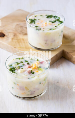 Soupe froide d'été traditionnel russe okroshka avec le kéfir dans les verres sur la table en bois blanc Banque D'Images