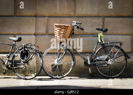 Vélo traditionnel avec panier appuyé contre le vieux mur de pierre d'un collège à l'Université de Cambridge UK en position feu Banque D'Images
