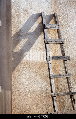 Une échelle s'appuie contre un mur. Le soleil jette une ombre forte Banque D'Images