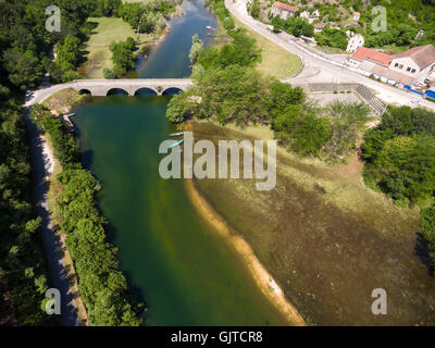 Petite ville est sur la rivière Crnojevica avec arch bridge voyage. Rivière qui coule dans le lac de Skadar. Monténégro Banque D'Images