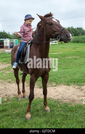 Petite fille de la campagne tente de contrôler le cheval à l'aide d'une bride Banque D'Images