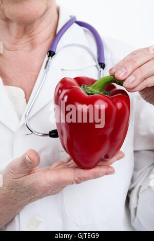 Gros poivron rouge en forme de cœur dans les mains du médecin, isolé sur fond blanc Banque D'Images