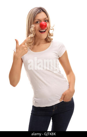 Smiling woman posing with a red clown nose et en montrant qu'il isolé sur fond blanc Banque D'Images