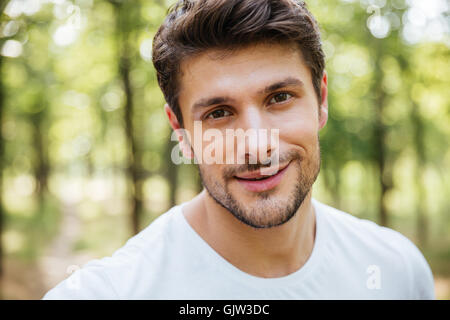 Gros plan du plaisir beau jeune homme portant un t-shirt blanc en forêt Banque D'Images