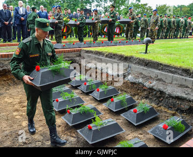 Lebus, Allemagne. Août 18, 2016. Un soldat russe places petites cercueils contenant les restes de soldats soviétiques de la seconde guerre mondiale dans une tombe, lors de leur enterrement au cimetière militaire à Lebus, Allemagne, 18 août 2016. Les 35 soldats de l'armée rouge sont morts dans des combats dans la région Oderbruch au début de 1945. Les dépouilles ont été récupérés par la Commission des sépultures de guerre allemande l'année dernière, et peut enfin être mis en terre, plus de 70 ans après la fin de la guerre. Photo : PATRICK PLEUL/DPA/Alamy Live News Banque D'Images