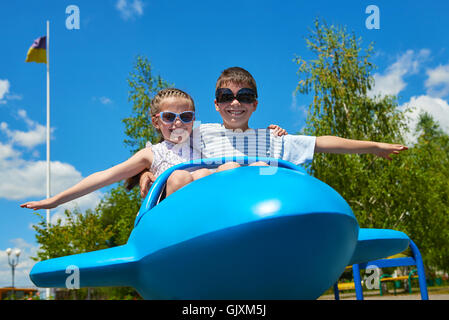 Deux enfants voler sur avion bleu attraction de parc, enfance heureuse, de l'été vacances Banque D'Images