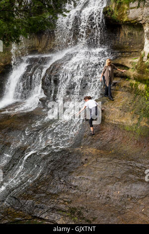 Sundell, Michigan - Touristes avec peut-être plus la bravoure que sens grimper sur les rochers humides adjacentes à rire Whitefish Falls. Banque D'Images