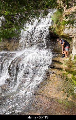 Sundell, Michigan - Touristes grimper derrière rire Whitefish Falls, qui chute de 100 pieds sur un escarpement calcaire. Banque D'Images