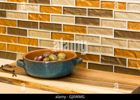 Accueil cuisine intérieur détail. Hors-d'olives dans un plat de service en céramique sur comptoir avec dosseret carreaux de mosaïque de verre. Banque D'Images