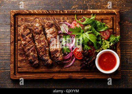 Lula grillé agneau kebab avec des oignons, de la salade et la tomate sauce épicée Satsebeli sur planche de bois Banque D'Images