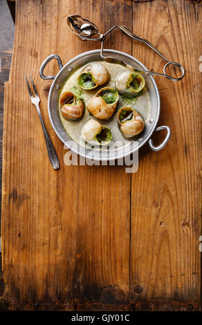 Escargots de Bourgogne escargots au beurre d'herbes en aluminium sur fond de bois rustique Banque D'Images