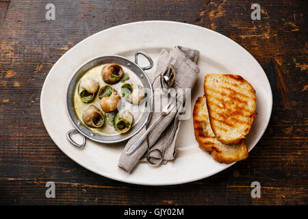 Escargots de Bourgogne escargots au beurre d'herbes en aluminium et toasts de pain on white plate Banque D'Images